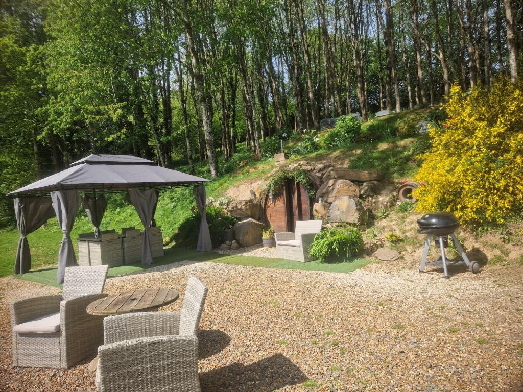 a patio with a gazebo and chairs and a grill at Gite sous-terre in Landisacq