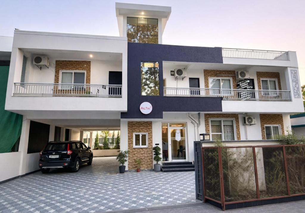 a house with a car parked in front of it at Live Free Hostel Dehradun in Dehradun