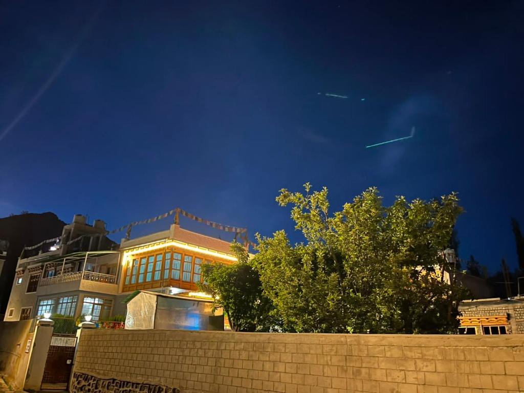 a large building at night with a brick wall at Chandan Guest House in Leh