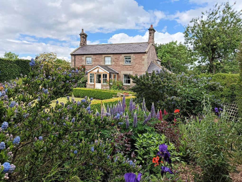 an old house with a garden and flowers at Lucker Mill House in Lucker
