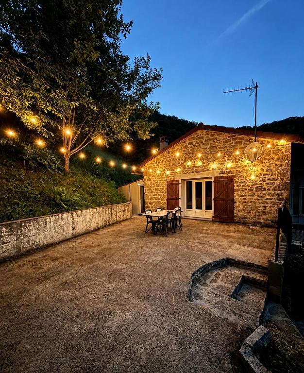 a patio with a table and lights on a building at Le petit repère in Jujurieux