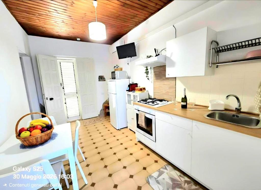 a kitchen with white cabinets and a basket of fruit on a table at La Casetta in Sarroch
