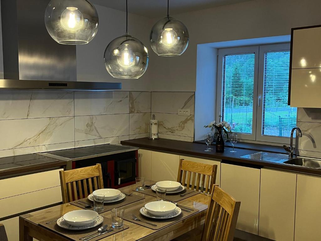 a kitchen with a wooden table with chairs and lights at Apartma 35 in Soča