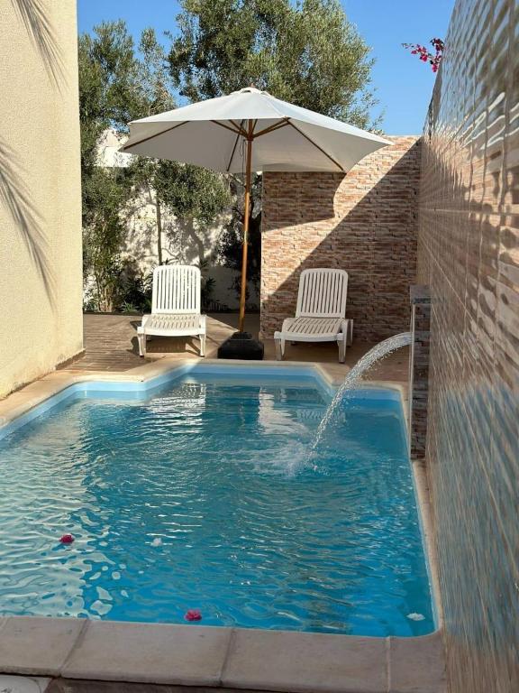 a swimming pool with an umbrella and two chairs at Villa cleopatra in Mezraya
