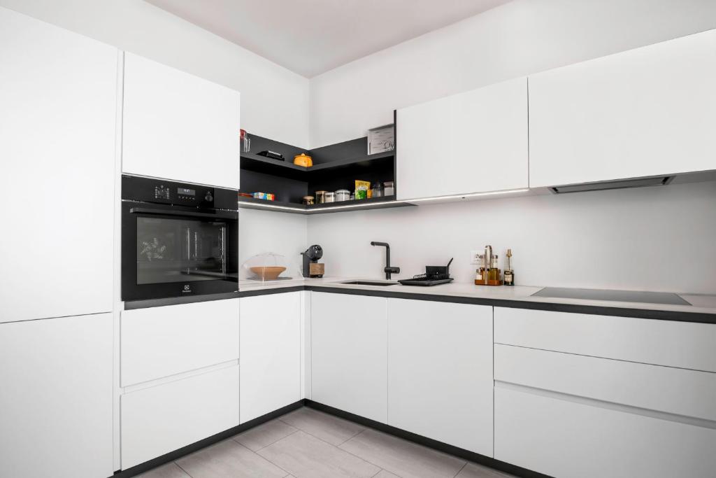 a kitchen with white cabinets and black appliances at Apartma Svetlo udobje v Piranu - Bright Comfort Apartment in Piran in Piran