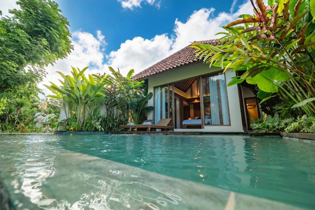 a villa with a swimming pool in front of a house at Apittoya Villas in Gianyar
