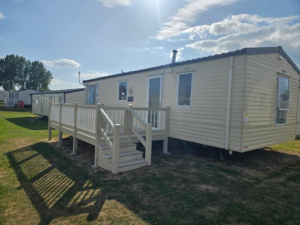 a white mobile home with a porch and stairs at 3 bed static van with decking in Dymchurch
