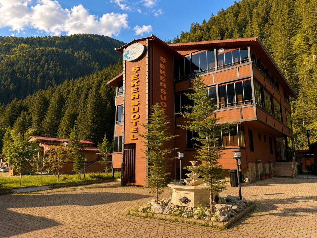a building with a clock tower in front of it at Şekersu Otel in Çaykara