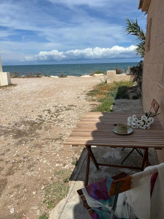 a picnic table on a beach with the ocean at La barraca del pescador in Denia