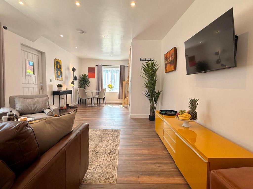 a living room with a couch and a tv on the wall at Unique Devon Cottages - Sunrise Cottage in Exmouth