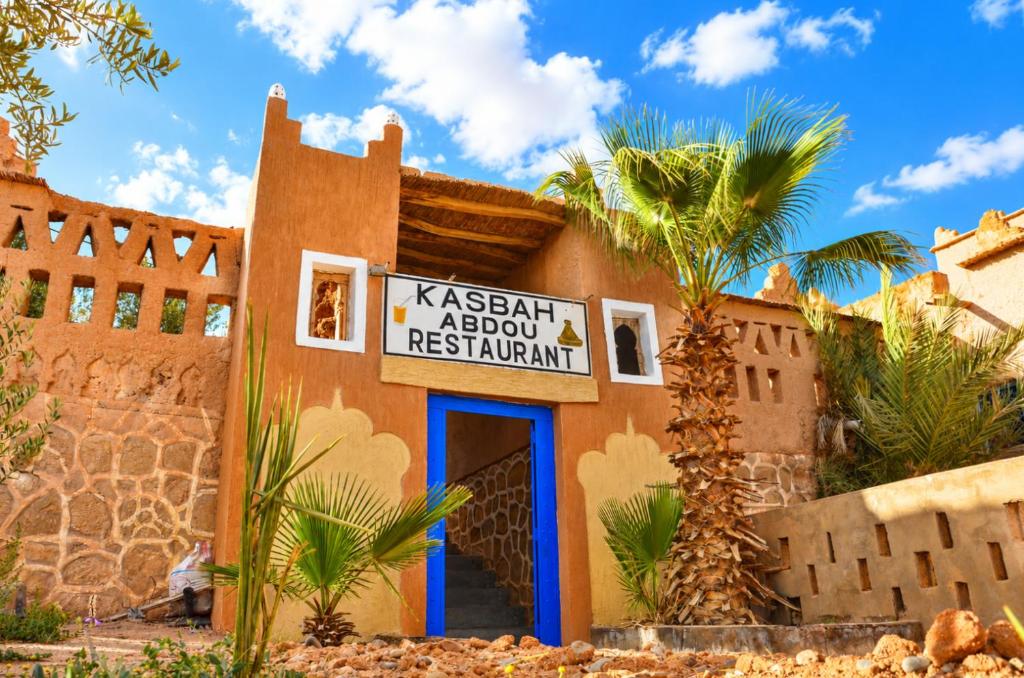 a building in the desert with a sign on it at Kasbah Abdou in El Kelaa des Mgouna