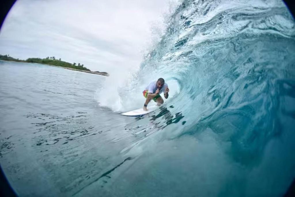 a man riding a wave on a surfboard in the ocean at Aasna Inn in Thulusdhoo