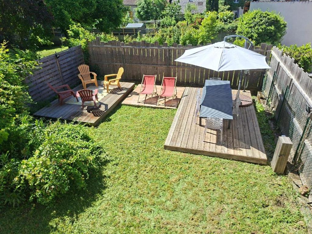 a backyard with a deck with chairs and an umbrella at havre de paix in Saint-Junien