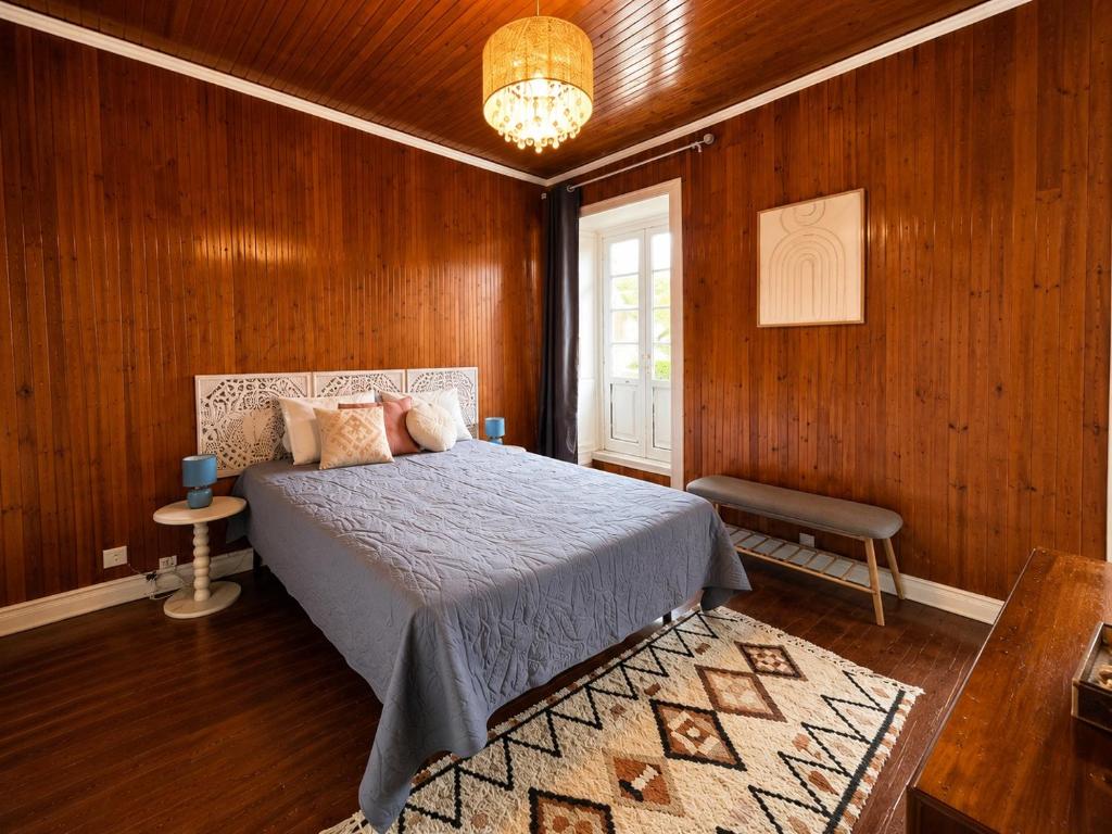 a bedroom with a bed in a wood paneled room at Botânico Guesthouse in Nordeste