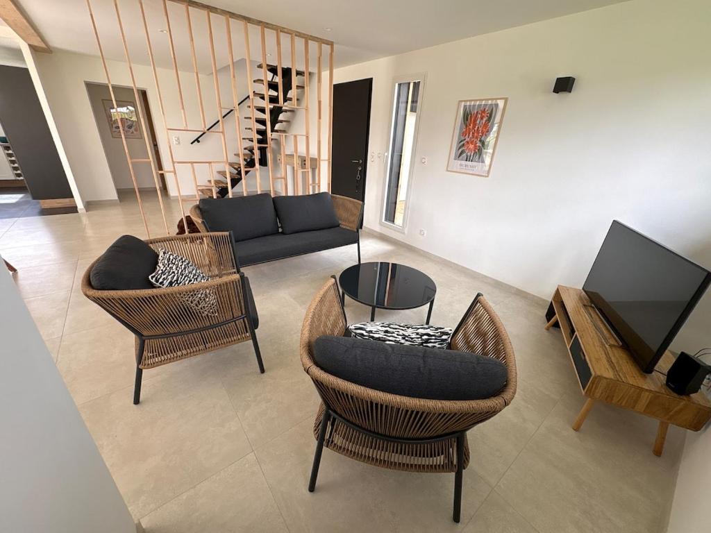 a living room with a couch and chairs and a television at Maison en bois moderne in Pléneuf-Val-André