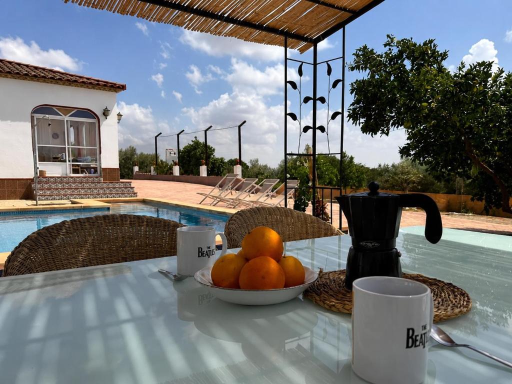 a table with a bowl of oranges and a tea pot at Antigua Villa Medina casa con piscina 3 habitaciones in Marchena