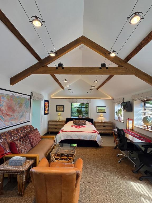 a bedroom with a bed and a couch and a desk at Spacious Studio - Bicester Village & Silverstone in Middleton Stoney