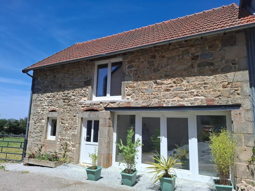 a stone house with large windows and potted plants at Faugere in Bussières