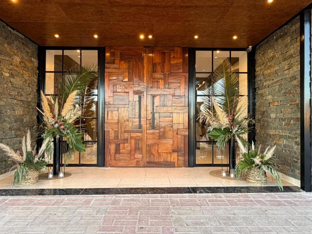 a lobby with a wooden door with two potted plants at Takuá Hotel Serrano in La Punta