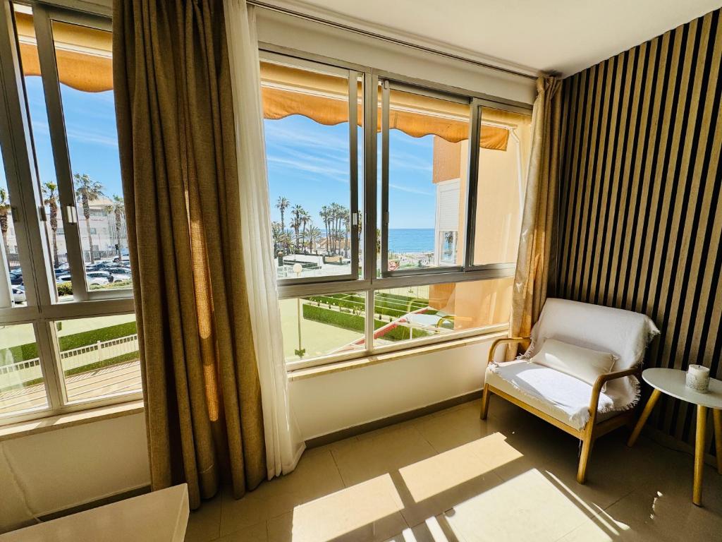 a room with a window with a chair and a view of the ocean at Brisa Mediterránea Torrox Costa in Torrox Costa