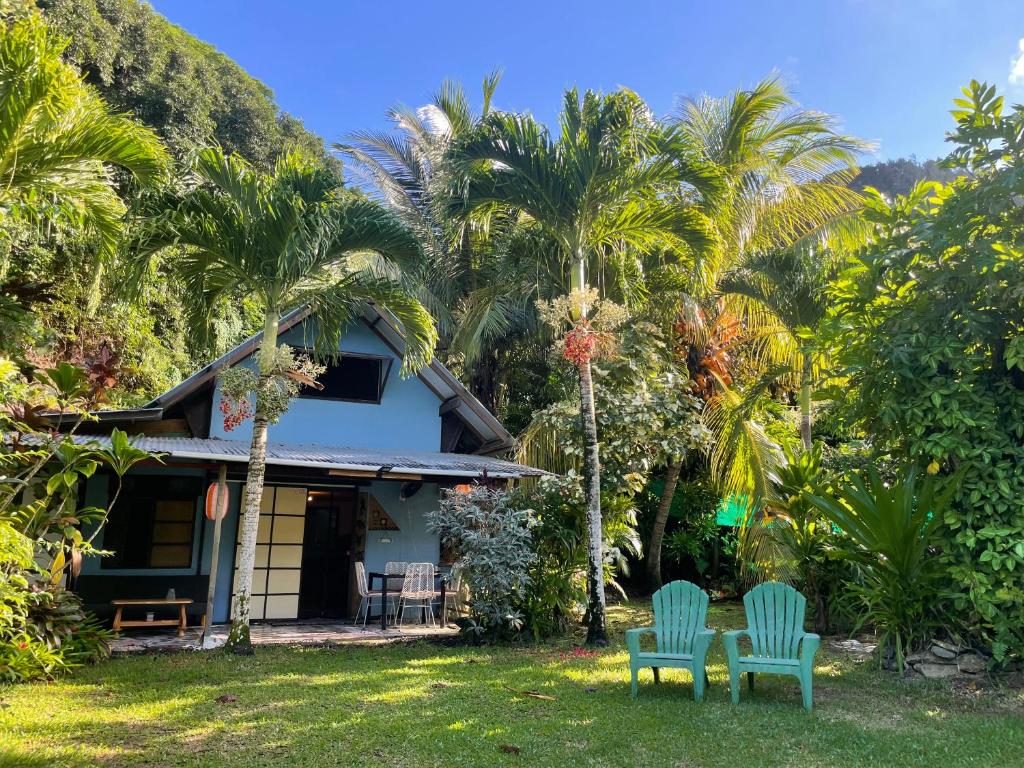 two chairs in front of a house with palm trees at Franky's Fare in Fare
