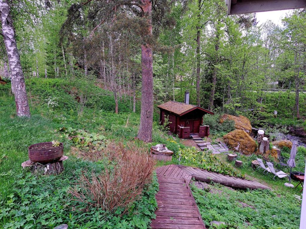 a wooden path through a forest with a wooden hut at Peaceful riverside cottage with sauna in Myllykylä