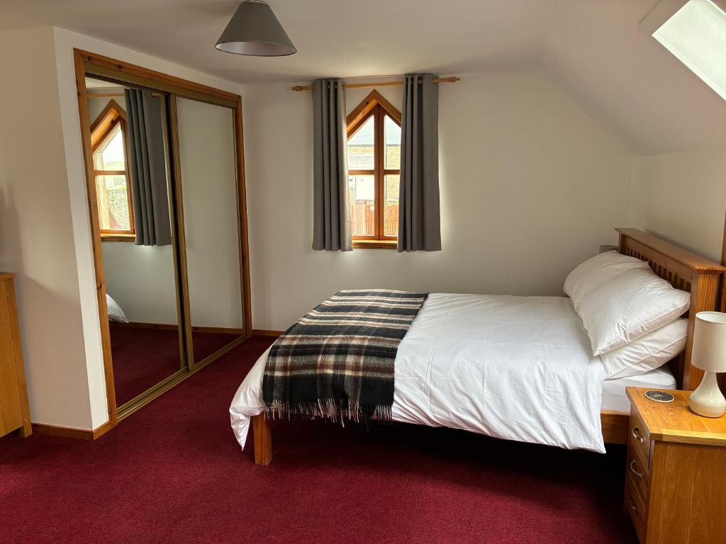 a bedroom with a bed and a mirror at Lotties Neuk in Lerwick