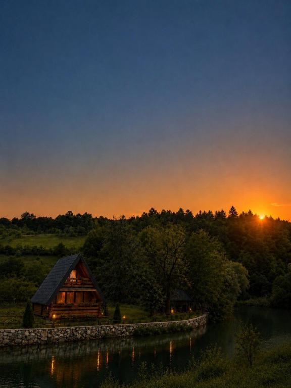 a cabin on the shore of a lake at sunset at Vikendica Ema in Šipovo