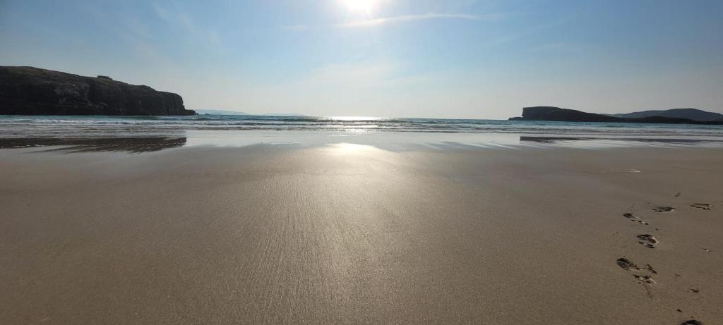 a view of a beach with footprints in the sand at Mackenzie Cottage, Kinlochbervie in Oldshore