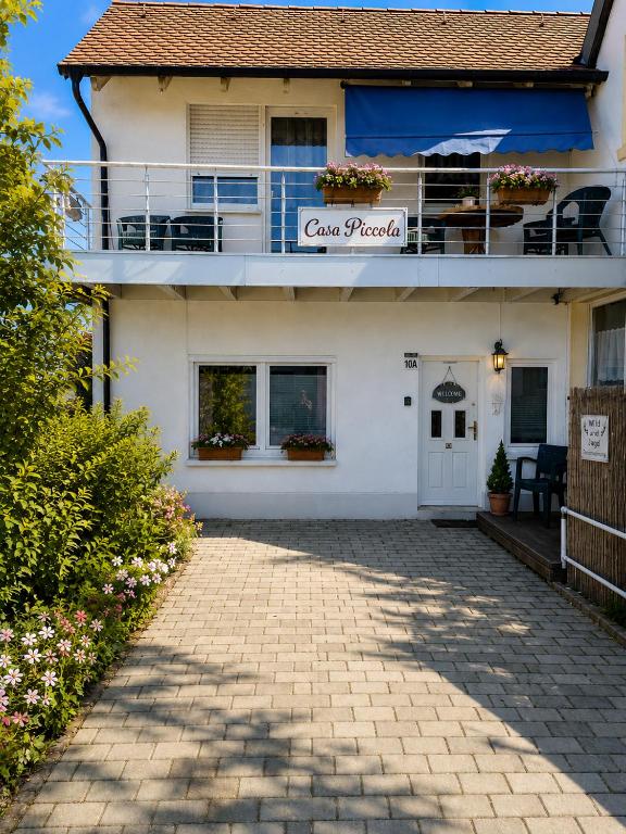 biały budynek z balkonem i patio w obiekcie Casa Piccola w mieście Strullendorf