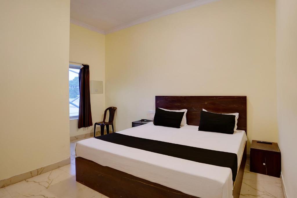 a bedroom with a large white bed with black pillows at Hotel O Maa JP Tower in Jabalpur