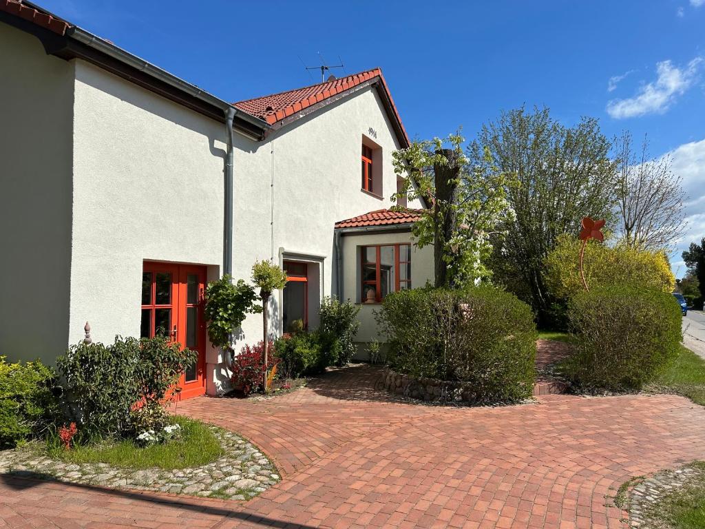 a white house with red doors and a brick driveway at Fuchsbau-eine Auszeit für die Seele in Kritzmow