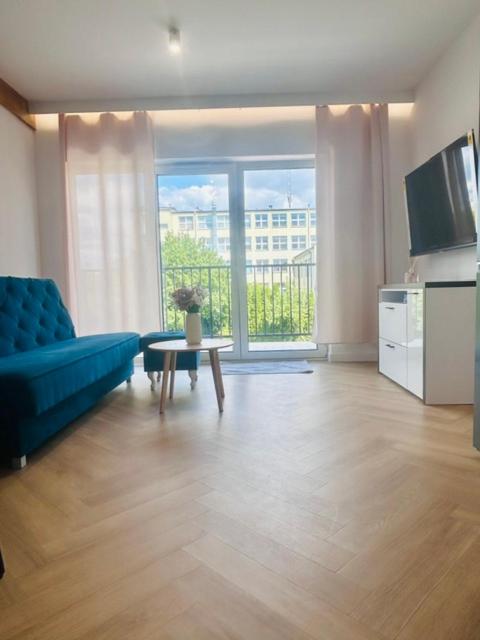 a living room with a blue couch and a table at Apartament Drohiczyńska in Siemiatycze