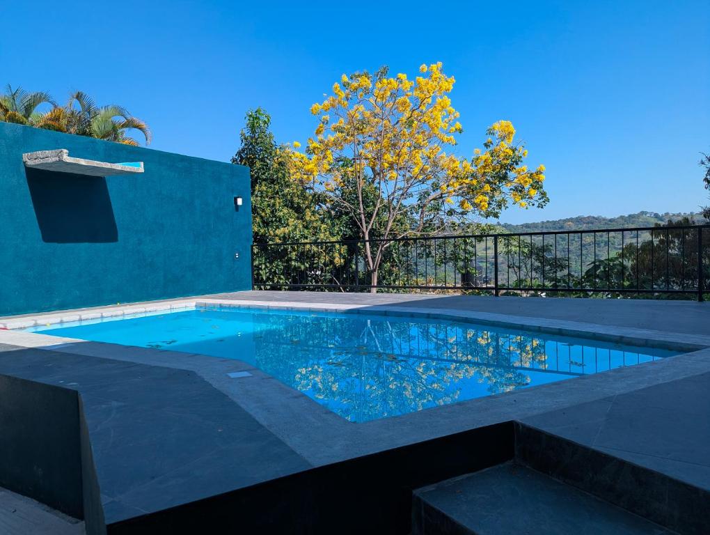 a swimming pool in a backyard with a blue wall at Céntrica habitación 2 camas queen - Gran Nehtolli #7 - Sin Estacionamiento in Xilitla
