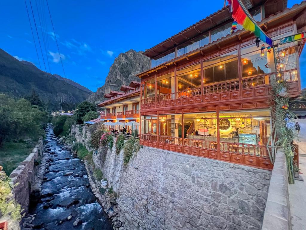 a building next to a river next to a mountain at Sol Ollantay Boutique Hotel in Ollantaytambo