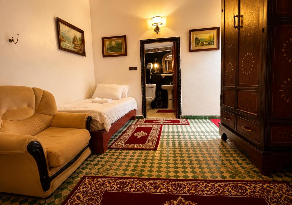 a room with a bed and a couch and a mirror at Dar Albanin in Fez