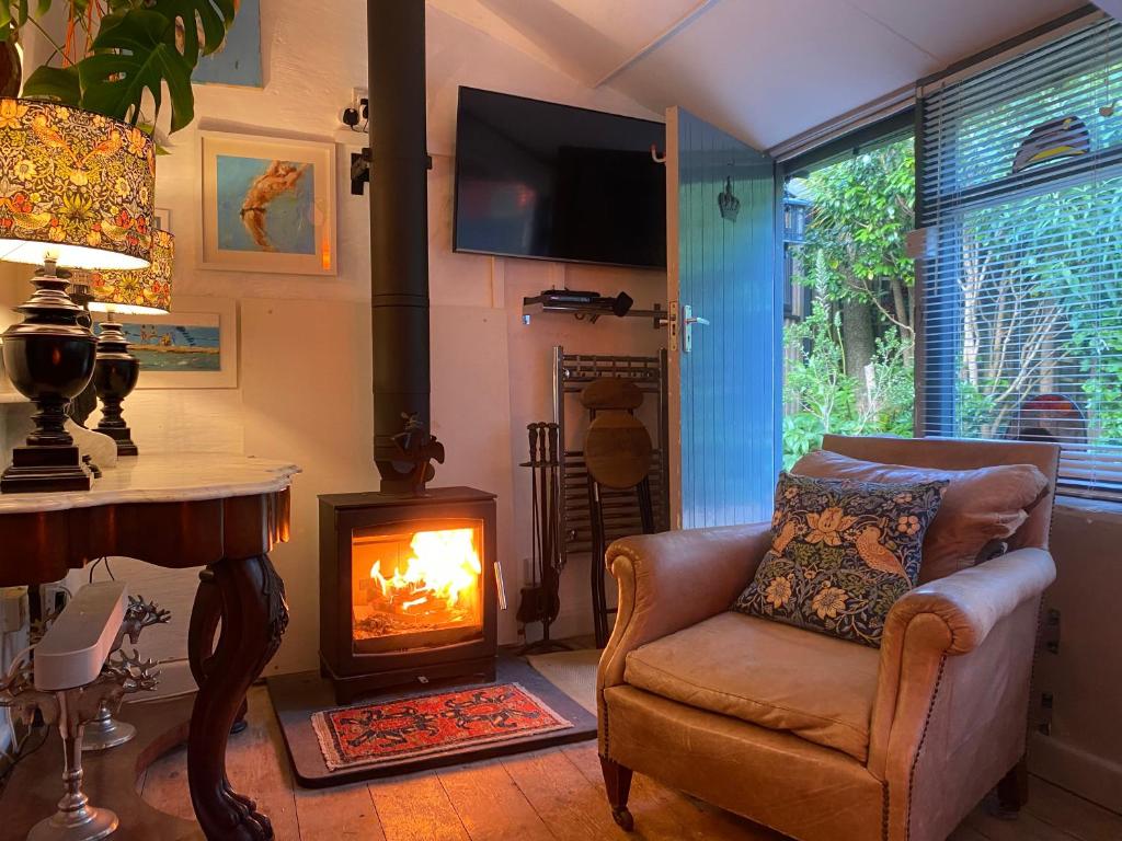 a living room with a chair and a fireplace at Spacious Studio by the sea, Garden & Parking in Marazion