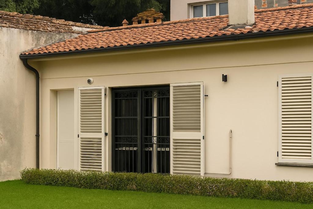 a white house with shuttered windows and green grass at Ground floor house in Castel Bolognese