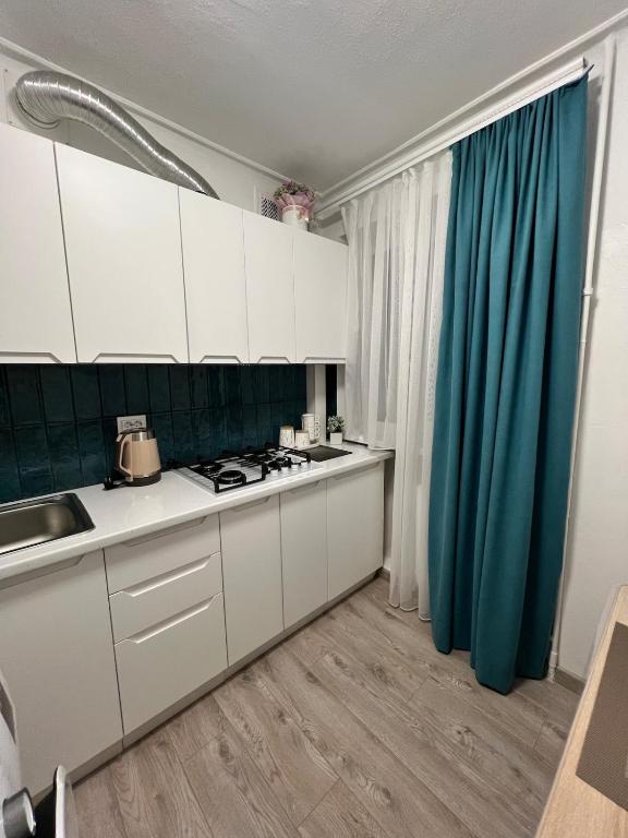 a kitchen with white cabinets and a blue curtain at Mykolaichuka in Chernivtsi