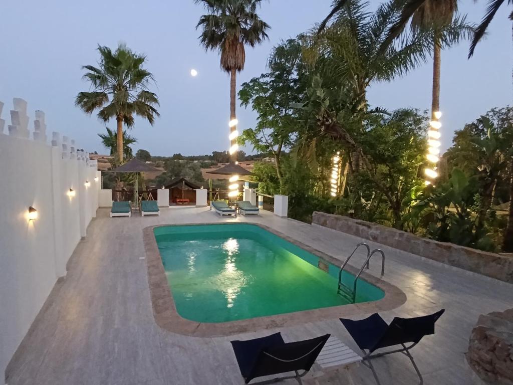 a swimming pool in the backyard of a house with palm trees at daryemma2 in Asilah