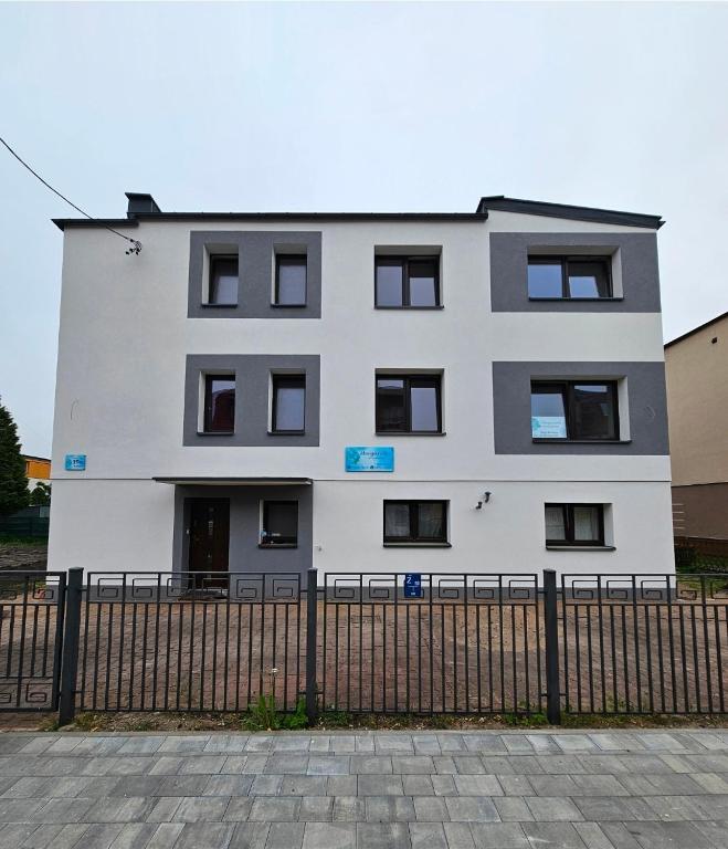 a white building with black windows behind a fence at Margaretka in Łeba