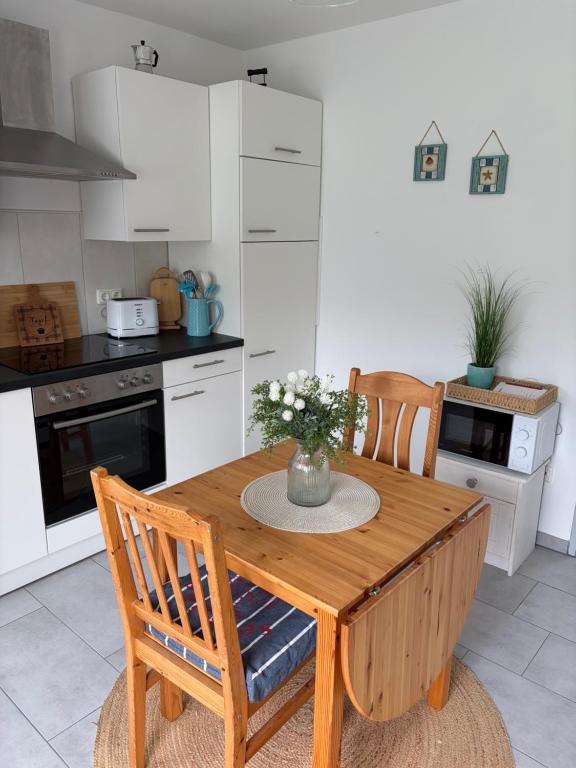 a kitchen with a wooden table with a vase of flowers on it at Ferienhuus Tüütje in Wolthusen