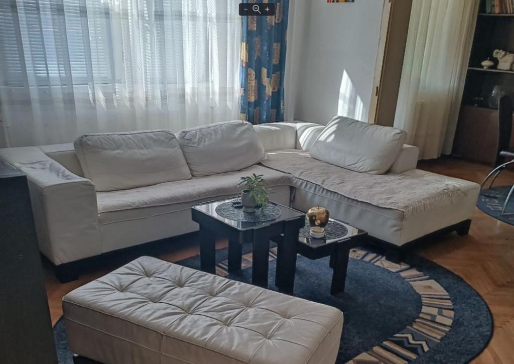 a living room with a white couch and a table at Apartman Kali Leskovac in Leskovac