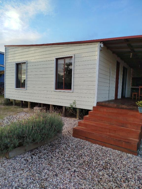 a small white house with a wooden deck at casa Andylu in Punta Del Diablo