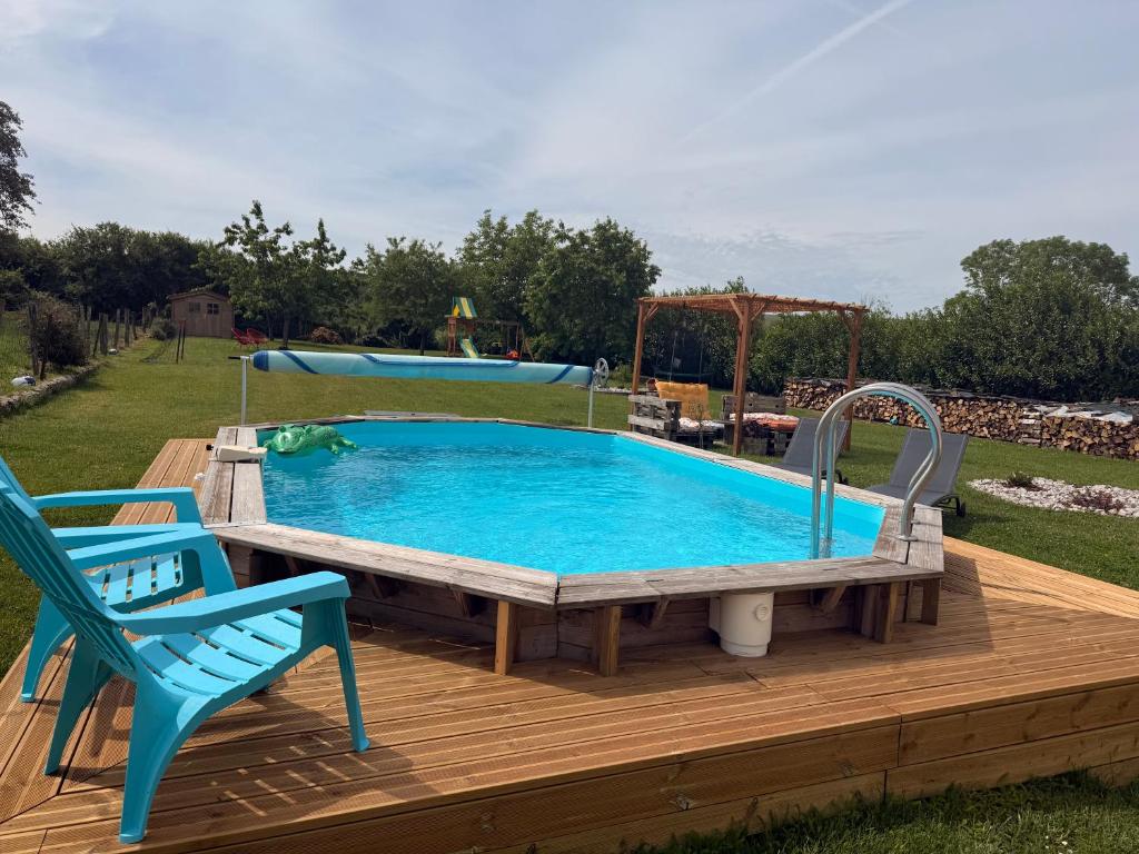 a pool with a table and a chair on a deck at Les volets bleus in Cierges