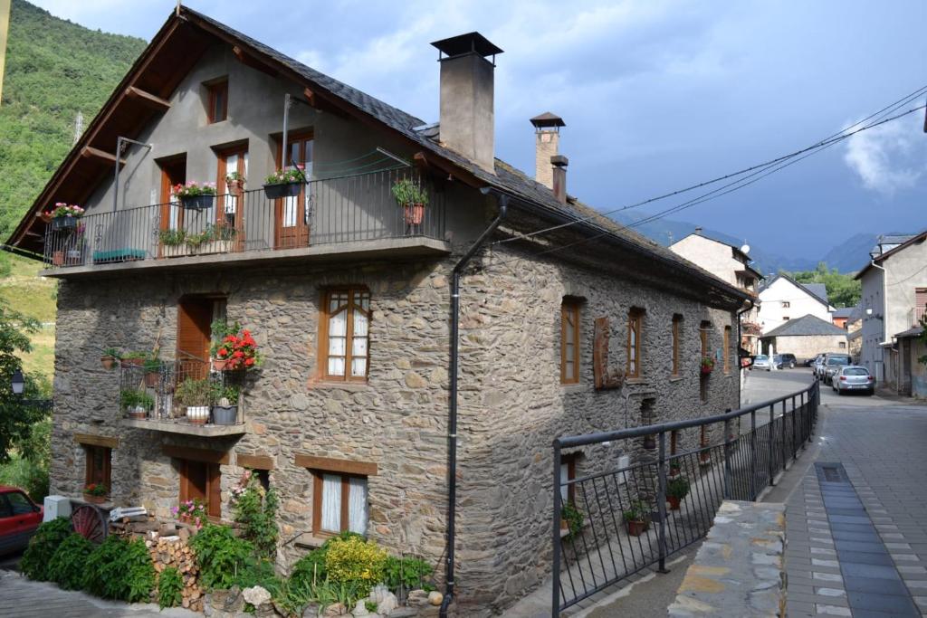 an old stone house with flower boxes on the windows at Casa Campaner in Valencia de Aneu