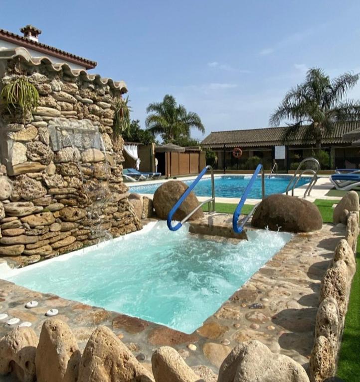 a pool with a rock wall and a slide in a yard at Residencial La Teja in Zahora