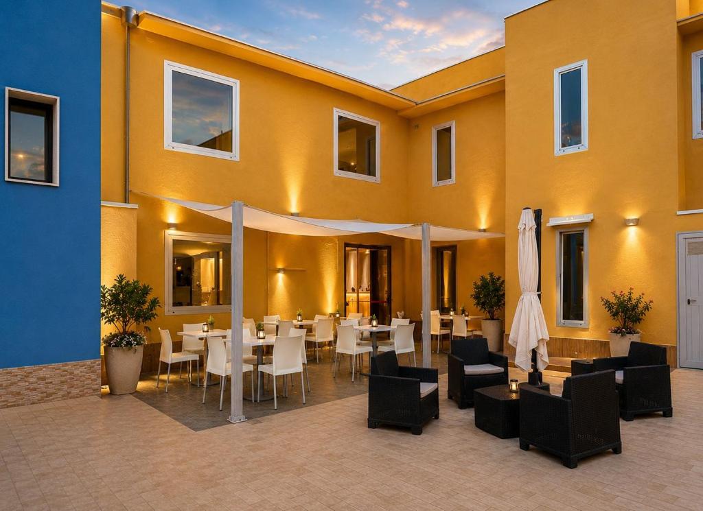a restaurant with white tables and chairs and a building at Hotel San Martino in Cassibile
