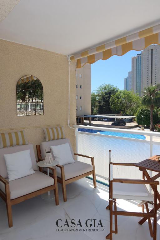 a balcony with chairs and tables and a swimming pool at CASA GIA l Luxury apartment Benidorm in Benidorm