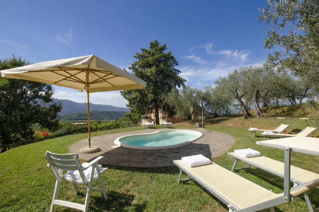 a pool with an umbrella and two chairs and a table at Fontesecca - Happy Rentals in Città della Pieve